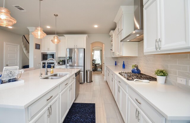 8703 Silver Crest Ln, Missouri City, TX 77459 - kitchen with wall chimney exhaust hood, appliances with stainless steel finishes, arched walkways, backsplash, and recessed lighting
