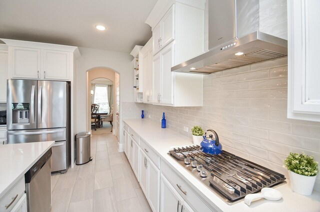 8703 Silver Crest Ln, Missouri City, TX 77459 - kitchen with wall chimney exhaust hood, appliances with stainless steel finishes, arched walkways, light countertops, and recessed lighting