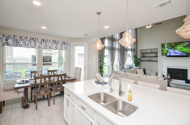 8703 Silver Crest Ln, Missouri City, TX 77459 - kitchen with light countertops, pendant lighting, white cabinetry, a fireplace, and open floor plan