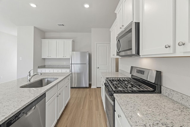 1035 Rosewood Trl, Beasley, TX 77417 - kitchen with appliances with stainless steel finishes, white cabinetry, light wood-style floors, light stone counters, and recessed lighting