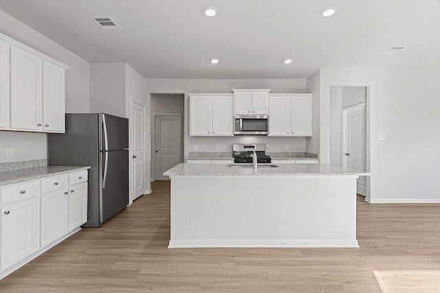 1035 Rosewood Trl, Beasley, TX 77417 - kitchen with appliances with stainless steel finishes, white cabinets, light wood-style floors, recessed lighting, and an island with sink
