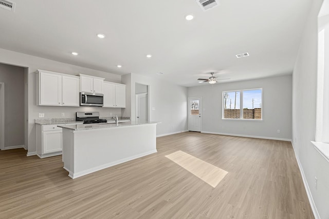 1035 Rosewood Trl, Beasley, TX 77417 - kitchen with appliances with stainless steel finishes, ceiling fan, white cabinets, light wood finished floors, and recessed lighting