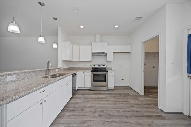 7430 N Star St, Houston, TX 77088 - kitchen featuring appliances with stainless steel finishes, under cabinet range hood, white cabinets, light stone counters, and light wood-style flooring