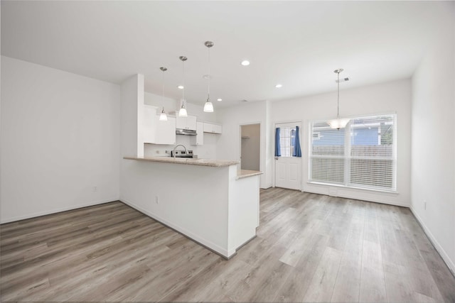 7430 N Star St, Houston, TX 77088 - kitchen featuring a peninsula, recessed lighting, white cabinetry, light wood finished floors, and hanging light fixtures