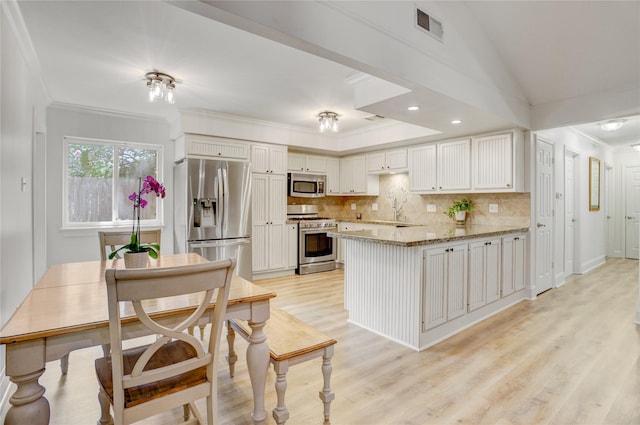 1410 Del Norte St, Houston, TX 77018 - kitchen with appliances with stainless steel finishes, a peninsula, tasteful backsplash, light wood finished floors, and crown molding