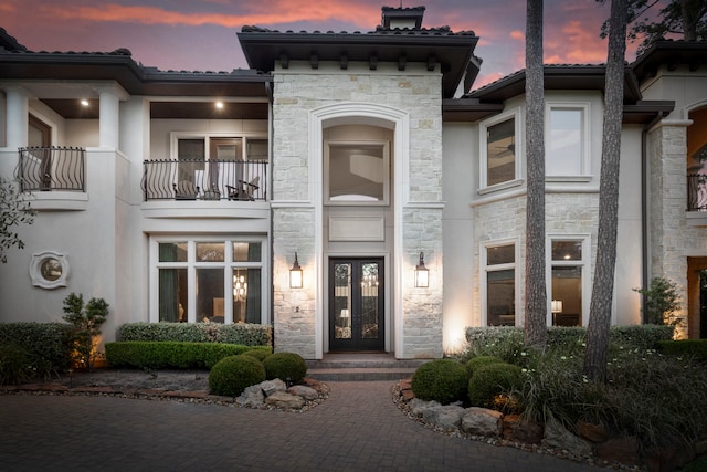 2 N Badger Lodge Cir, The Woodlands, TX 77389 - view of front facade with stone siding, french doors, stucco siding, and a balcony