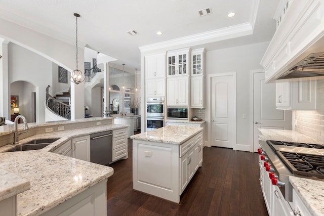 2 N Badger Lodge Cir, The Woodlands, TX 77389 - kitchen featuring arched walkways, appliances with stainless steel finishes, custom exhaust hood, a kitchen island, and decorative backsplash