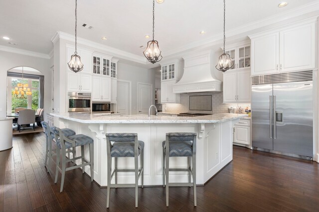 2 N Badger Lodge Cir, The Woodlands, TX 77389 - kitchen featuring built in appliances, a chandelier, custom exhaust hood, backsplash, and crown molding