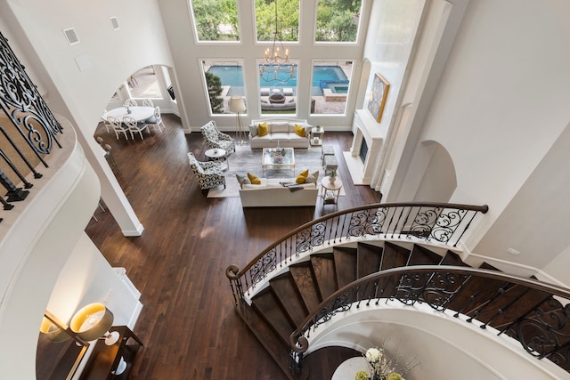 2 N Badger Lodge Cir, The Woodlands, TX 77389 - living room featuring hardwood / wood-style floors, stairs, a chandelier, a high ceiling, and arched walkways