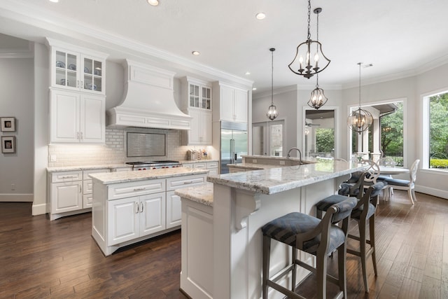 2 N Badger Lodge Cir, The Woodlands, TX 77389 - kitchen with stainless steel built in fridge, a large island, custom range hood, recessed lighting, and tasteful backsplash