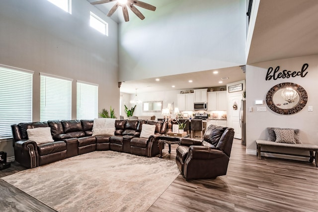 18202 Octavio Frias Trl, Houston, TX 77044 - living room with ceiling fan, wood finished floors, a chandelier, and a towering ceiling