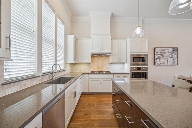 9520 London Bridge Sta, Houston, TX 77045 - kitchen featuring appliances with stainless steel finishes, white cabinetry, crown molding, light stone counters, and dark brown cabinets