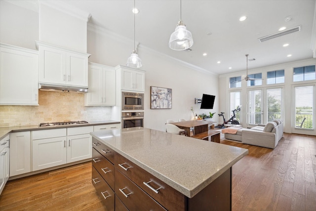 9520 London Bridge Sta, Houston, TX 77045 - kitchen with stainless steel appliances, crown molding, white cabinetry, decorative backsplash, and under cabinet range hood
