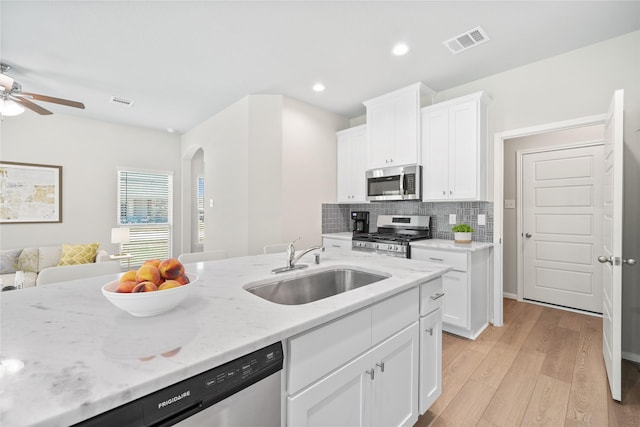 426 Emerald Thicket Ln, Huffman, TX 77336 - kitchen featuring appliances with stainless steel finishes, arched walkways, light wood-style floors, open floor plan, and white cabinetry