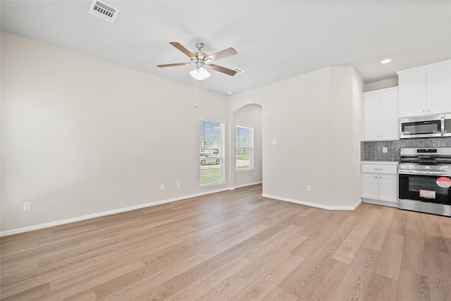 426 Emerald Thicket Ln, Huffman, TX 77336 - kitchen featuring appliances with stainless steel finishes, arched walkways, ceiling fan, tasteful backsplash, and light wood-style flooring