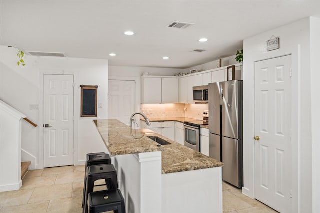 151 Anise Tree Pl, The Woodlands, TX 77382 - kitchen featuring appliances with stainless steel finishes, white cabinetry, recessed lighting, light stone counters, and decorative backsplash