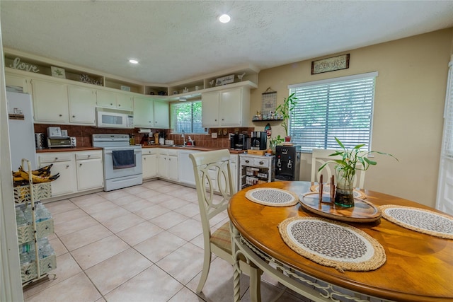16841 Aprilmont Dr, Sugar Land, TX 77498 - kitchen featuring white appliances, tasteful backsplash, light tile patterned flooring, white cabinets, and recessed lighting