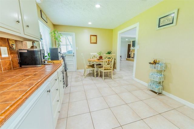 16841 Aprilmont Dr, Sugar Land, TX 77498 - kitchen with tile counters, white cabinetry, a textured ceiling, recessed lighting, and light tile patterned flooring