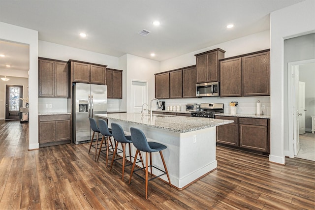 1818 Homewood Point Ln, Rosharon, TX 77583 - kitchen with appliances with stainless steel finishes, dark wood-style flooring, a kitchen island with sink, dark brown cabinets, and recessed lighting
