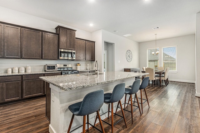 1818 Homewood Point Ln, Rosharon, TX 77583 - kitchen with stainless steel appliances, dark wood finished floors, light stone countertops, a kitchen breakfast bar, and dark brown cabinetry