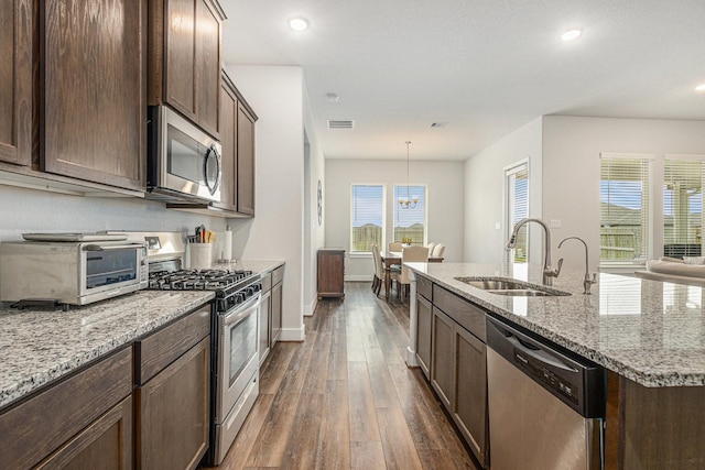 1818 Homewood Point Ln, Rosharon, TX 77583 - kitchen featuring dark wood-type flooring, appliances with stainless steel finishes, a center island with sink, light stone countertops, and dark brown cabinetry