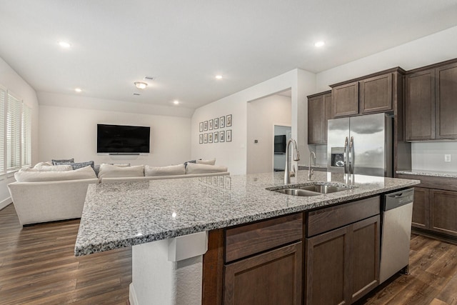 1818 Homewood Point Ln, Rosharon, TX 77583 - kitchen with appliances with stainless steel finishes, a center island with sink, dark wood-style floors, light stone countertops, and dark brown cabinets