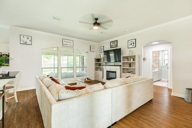 203 Poppy St, Lake Jackson, TX 77566 - living room featuring a glass covered fireplace, arched walkways, a ceiling fan, wood finished floors, and crown molding
