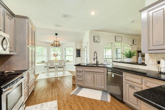 203 Poppy St, Lake Jackson, TX 77566 - kitchen with stainless steel appliances, light wood-style floors, tasteful backsplash, a chandelier, and hanging light fixtures