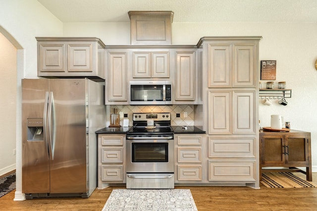 203 Poppy St, Lake Jackson, TX 77566 - kitchen featuring stainless steel appliances, light wood finished floors, decorative backsplash, and arched walkways
