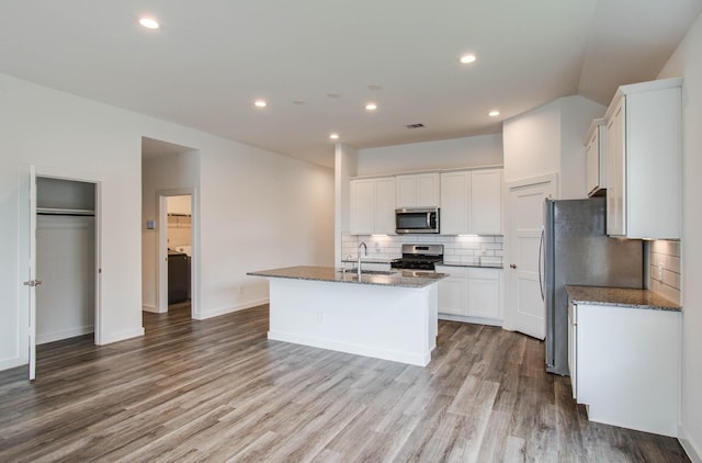 309 Pleasant Hill Way, Conroe, TX 77304 - kitchen with appliances with stainless steel finishes, tasteful backsplash, dark stone counters, a kitchen island with sink, and recessed lighting