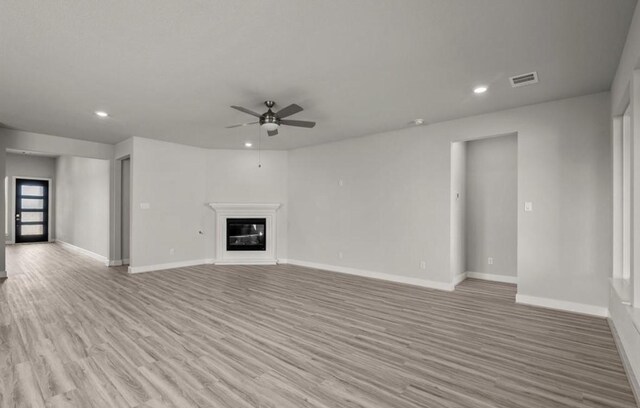 7827 Albury Mnr, Richmond, TX 77407 - unfurnished living room with a ceiling fan, light wood finished floors, recessed lighting, and a glass covered fireplace
