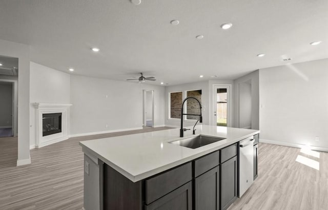 7827 Albury Mnr, Richmond, TX 77407 - kitchen with light wood-style floors, stainless steel dishwasher, a kitchen island with sink, light countertops, and recessed lighting