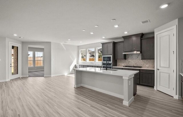 7827 Albury Mnr, Richmond, TX 77407 - kitchen featuring stainless steel appliances, recessed lighting, a center island with sink, light wood-style floors, and light countertops