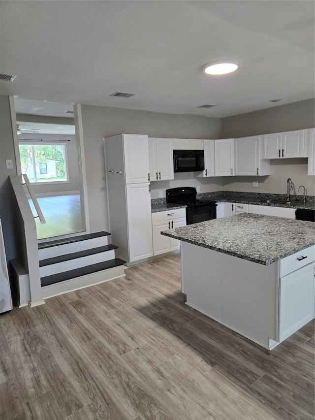 204 Jasmine St, Lake Jackson, TX 77566 - kitchen featuring black appliances, white cabinets, a center island, stone countertops, and light wood finished floors