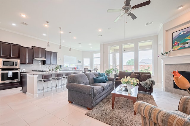 25603 Kearsley Dr, Katy, TX 77494 - living room featuring light tile patterned flooring, crown molding, a ceiling fan, recessed lighting, and a tile fireplace