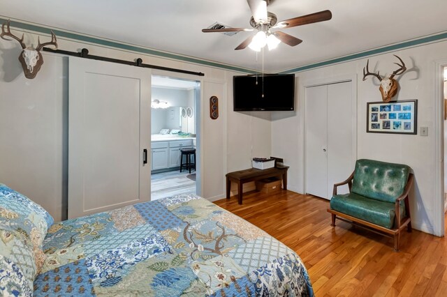 820 Meadow Ln, Wharton, TX 77488 - bedroom featuring light wood-style flooring, a closet, ceiling fan, and a barn door