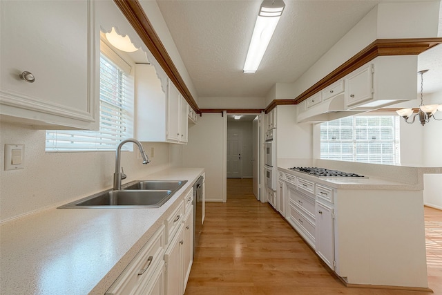 2510 Wind Fall Ln, Sugar Land, TX 77479 - kitchen featuring white cabinetry, light countertops, light wood-style floors, a chandelier, and a textured ceiling