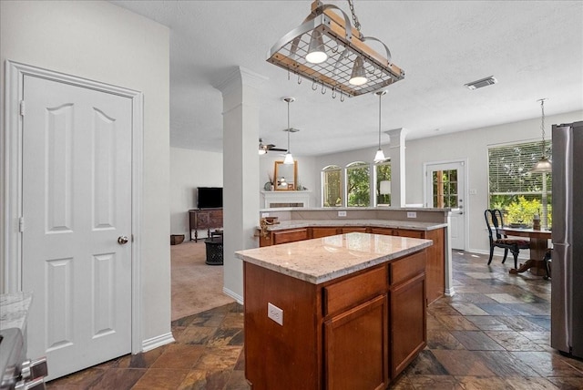 1427 Roaring Springs Ln, Seabrook, TX 77586 - kitchen with stone tile floors, freestanding refrigerator, a center island, decorative light fixtures, and brown cabinets