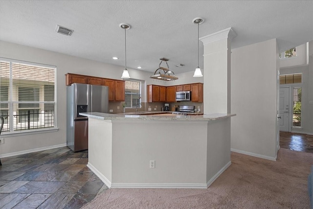 1427 Roaring Springs Ln, Seabrook, TX 77586 - kitchen with stainless steel appliances, brown cabinets, decorative light fixtures, a center island, and a textured ceiling