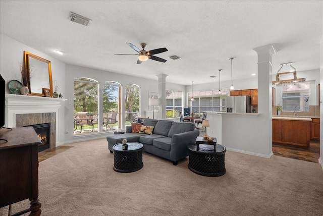 1427 Roaring Springs Ln, Seabrook, TX 77586 - living room with carpet floors, a ceiling fan, a tile fireplace, ornate columns, and a textured ceiling