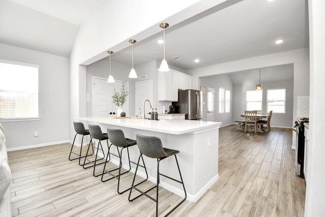8419 Sunset Horizon Dr, Baytown, TX 77521 - kitchen with appliances with stainless steel finishes, vaulted ceiling, white cabinetry, a breakfast bar area, and light wood-style floors