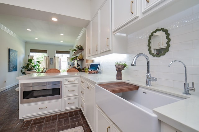 987 S Post Oak Ln, Houston, TX 77056 - kitchen with ornamental molding, white cabinetry, backsplash, a peninsula, and brick patterned flooring