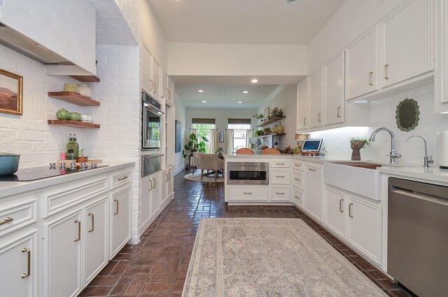987 S Post Oak Ln, Houston, TX 77056 - kitchen featuring stainless steel dishwasher, black electric cooktop, light countertops, white cabinets, and backsplash