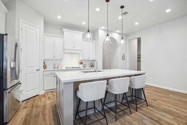 1523 Carson Field Ln, Richmond, TX 77469 - kitchen featuring stainless steel refrigerator with ice dispenser, light wood-style flooring, tasteful backsplash, light countertops, and white cabinetry
