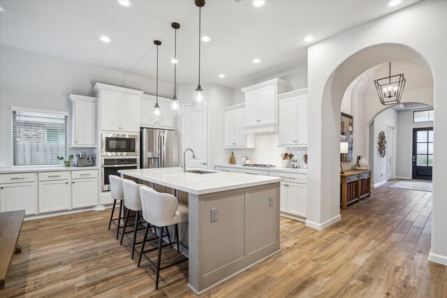 1523 Carson Field Ln, Richmond, TX 77469 - kitchen featuring stainless steel appliances, arched walkways, tasteful backsplash, a kitchen breakfast bar, and white cabinetry