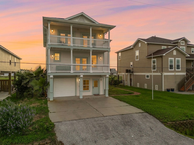 710 93rd St, Galveston, TX 77554 - raised beach house featuring a balcony, driveway, an attached garage, and a lawn