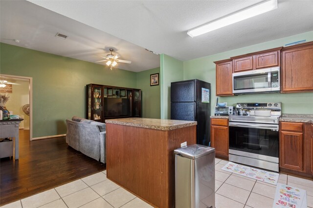 4710 Palm Park Ln, Richmond, TX 77469 - kitchen featuring appliances with stainless steel finishes, ceiling fan, light tile patterned flooring, open floor plan, and a kitchen island