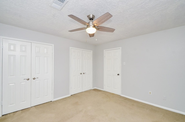 9719 Kindletree Dr, Houston, TX 77040 - unfurnished bedroom featuring multiple closets, light carpet, a textured ceiling, and ceiling fan