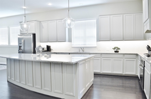 9323 Stablewood Lakes Ln, Tomball, TX 77375 - kitchen featuring appliances with stainless steel finishes, a kitchen island, white cabinets, dark wood-style floors, and tasteful backsplash