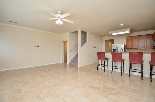 19038 Winding Stream Ln, Houston, TX 77084 - kitchen with stainless steel fridge, a kitchen bar, ornamental molding, a ceiling fan, and backsplash